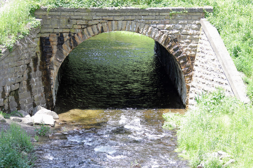 89246484 - water flows over a dam and through this stone tunnel.
